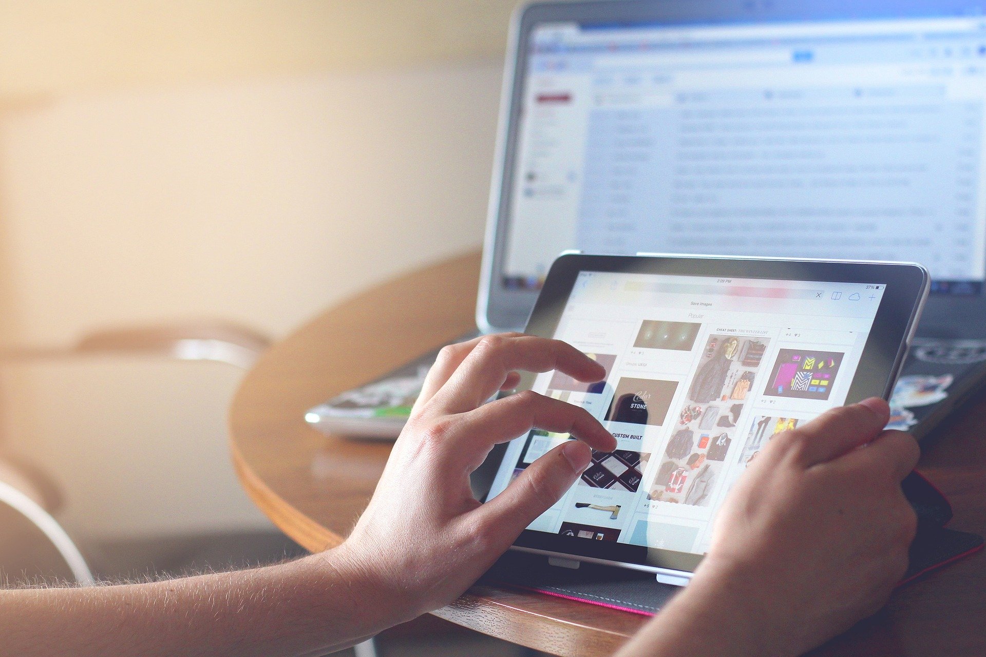 woman-holding-tablet-with-a-laptop-in-the-background